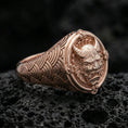 Load image into Gallery viewer, Rose gold plated oni mask ring with seigaiha wave design band and detailed horned demon face centerpiece, close-up on black volcanic stone