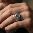 Load image into Gallery viewer, Polished silver Japanese oni signet ring on the finger with seigaiha wave band engraving, wearable macro emphasizing the framed demon face