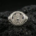 Load image into Gallery viewer, Sterling silver US eagle seal signet ring in a polished silver finish, high-relief emblem with shield and wreath details, close-up on volcanic stone