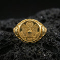 Load image into Gallery viewer, Sterling silver US eagle seal signet ring with a gold plated finish, engraved crest design with shield and laurel elements, macro on volcanic rock