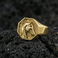 Load image into Gallery viewer, Gold plated horse signet ring on porous volcanic stone, premium dark background emphasizing the carved equestrian profile