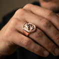 Load image into Gallery viewer, Rose gold plated wolf signet ring on finger, close-up lifestyle photo showcasing the shield-shaped top and engraved wolf details