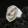 Load image into Gallery viewer, Polished silver wolf head signet ring on volcanic rock surface, studio close-up highlighting crisp bezel edges and realistic animal relief