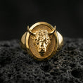 Load image into Gallery viewer, Gold plated bull signet ring on porous volcanic stone, premium dark background emphasizing the horns and bold animal portrait