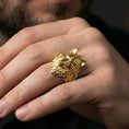 Load image into Gallery viewer, Gold plated wolf ring worn on a finger with a dark minimal background, showing strong contrast and depth