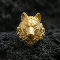 Load image into Gallery viewer, Detailed gold plated wolf head ring photographed on black volcanic stone with sharp focus and dramatic shadows