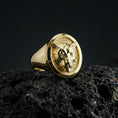Load image into Gallery viewer, Gold plated leopard signet ring on porous volcanic stone, premium dark studio shot emphasizing the bold big cat relief and classic round signet silhouette
