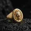 Load image into Gallery viewer, Gold plated lion signet ring on volcanic rock in a dark studio setting, detailed macro shot emphasizing the sculpted lion face and high-contrast texture