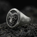 Load image into Gallery viewer, Close-up of an oxidized sterling silver ram signet ring on porous volcanic rock with dark premium lighting