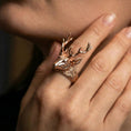 Load image into Gallery viewer, Rose gold plated stag head ring worn on a finger, macro view focusing on the face and antler craftsmanship