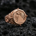 Load image into Gallery viewer, Sterling silver pyramid eye signet ring with a rose gold plated finish, bold round medallion face and engraved mystical rays, close-up on volcanic rock