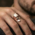 Load image into Gallery viewer, Sterling silver Spartan helm ring on a finger, macro lifestyle shot featuring the rose gold plated finish and battle-worn cracked helmet detailing