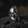Load image into Gallery viewer, Sterling silver Spartan warrior helmet signet ring with an oxidized finish, ancient Greek helmet design with cracked texture detail, macro on black volcanic rock