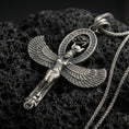Load image into Gallery viewer, Sterling silver Egyptian Isis winged pendant with an oxidized finish, goddess figure with spread wings and oval hieroglyph halo, close-up on black volcanic rock