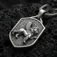 Load image into Gallery viewer, Sterling silver winged lion shield pendant with an oxidized finish, medieval heraldic griffin-style motif in raised relief, close-up on black volcanic rock