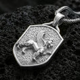 Load image into Gallery viewer, Sterling silver winged lion crest pendant in a polished silver finish, shield-shaped heraldic animal emblem with textured background, macro on volcanic stone