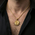 Load image into Gallery viewer, Gold plated Odin and raven medallion pendant necklace worn on the neck, lifestyle photo featuring warm tone finish and strong statement Viking medallion presence.