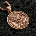 Load image into Gallery viewer, Rose gold plated imperial guardian lion pendant necklace on textured volcanic rock, centered studio-style close-up showcasing soft rosy glow and intricate fu dog relief with a defined geometric frame.