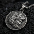 Load image into Gallery viewer, Oxidized Heracles lion helmet coin pendant necklace on textured volcanic rock, centered close-up highlighting the Greek key border, lion head hood, and deep antique shadowed contrast.
