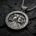 Load image into Gallery viewer, Oxidized Horus and Anubis pendant necklace on textured volcanic rock, centered close-up highlighting the two Egyptian gods in profile, carved hieroglyph border, and deep antique shadowed contrast.