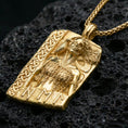 Load image into Gallery viewer, Gold plated Hel Norse goddess pendant necklace on textured volcanic rock, premium close-up with warm reflective shine across the half-skull portrait, braided border, and raised rune details.