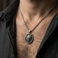 Load image into Gallery viewer, Oxidized demon mask medallion pendant necklace worn on the neck, lifestyle framing showing realistic scale and bold vintage contrast against the chest.