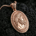 Load image into Gallery viewer, Rose gold plated Hades coin pendant necklace on textured volcanic rock, centered studio-style close-up showcasing soft rosy glow and intricate Greek mythology portrait detailing.
