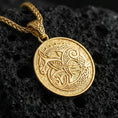 Load image into Gallery viewer, Gold plated Urnes style Viking beast pendant necklace on textured volcanic rock, premium close-up with warm reflective shine across the intertwined beast figure and detailed Nordic knotwork border.