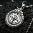 Load image into Gallery viewer, Polished silver dragon ouroboros compass necklace on volcanic stone, macro lighting highlighting the scaled coil details