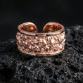 Load image into Gallery viewer, Rose gold plated skull cuff ring on textured volcanic rock, centered studio-style close-up showcasing soft rosy glow and crisp skull detailing with a refined finish.