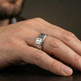 Load image into Gallery viewer, Polished silver Egyptian symbols band ring worn on a finger, clean lifestyle wear shot capturing bright shine and the detailed Eye of Horus and ankh engraving in natural light.