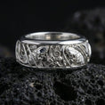 Load image into Gallery viewer, Polished silver koi fish and lotus band ring on textured volcanic rock, crisp macro product photo emphasizing clean edges, sharp scale engraving, and bright reflective highlights across the koi-and-lotus details.