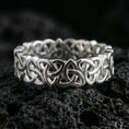 Load image into Gallery viewer, Polished silver Celtic triquetra chain-link ring on textured volcanic rock, crisp macro product photo emphasizing clean edges, sharp interlace geometry, and bright reflective highlights across the linked pattern.