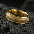 Load image into Gallery viewer, Gold plated woven texture band ring on textured volcanic rock, premium close-up showing warm gold tone across the braided surface and smooth edges.