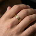 Load image into Gallery viewer, Gold plated Celtic knot band ring worn on a finger, lifestyle photo capturing warm reflective finish and clear visibility of the interwoven design.