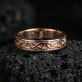 Load image into Gallery viewer, Rose gold plated Celtic knot band ring on volcanic stone, refined macro shot with soft rosy highlights and detailed interlaced knot engraving.