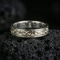 Load image into Gallery viewer, Polished silver Celtic knot band ring on volcanic stone, sharp macro product photo emphasizing clean reflective edges and crisp knotwork relief.