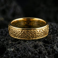 Load image into Gallery viewer, Gold plated Celtic knot band ring on volcanic stone, premium macro shot showing warm gold tone across the woven knot pattern and smooth rounded profile.