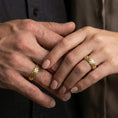 Load image into Gallery viewer, Gold plated woven texture band ring worn on a finger, lifestyle wear image capturing warm reflective finish and the woven grid pattern clearly.