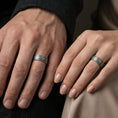Load image into Gallery viewer, Oxidized Damascus-style band ring worn on a man and woman's finger, lifestyle wear photo showing strong contrast between darkened grooves and raised grain lines.