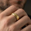 Load image into Gallery viewer, Gold plated Damascus-style band ring worn on a finger, lifestyle image featuring warm reflective finish and clearly visible layered grain lines.