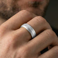 Load image into Gallery viewer, Polished silver Damascus-style band ring worn on a finger, lifestyle shot capturing bright shine and the flowing woodgrain pattern in natural light.