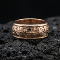 Load image into Gallery viewer, Rose gold plated hieroglyph band ring on volcanic stone, refined macro shot featuring soft rosy highlights and sharp hieroglyph engraving depth.