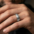Load image into Gallery viewer, Polished silver fleur-de-lis band ring worn on a finger, lifestyle shot capturing the glossy finish and clear medieval motif in natural light.