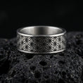 Load image into Gallery viewer, Oxidized sterling silver geometric floral band ring on volcanic stone, macro close-up highlighting the darkened engraved lattice pattern and crisp edges.