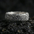 Load image into Gallery viewer, Oxidized sterling silver scrollwork band ring on volcanic stone, macro close-up highlighting deep engraved swirls and dark contrast.