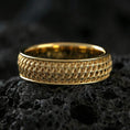 Load image into Gallery viewer, Gold plated geometric weave band ring on volcanic stone, premium close-up showing warm gold tone across the structured interwoven design.