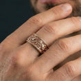 Load image into Gallery viewer, Rose gold plated mythic faces cuff band ring worn on a finger, lifestyle image highlighting elegant rose tone and the ornate portrait detailing for a premium look.