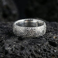 Load image into Gallery viewer, Polished silver wave pattern band ring on volcanic stone, clean studio macro emphasizing crisp engraved lines, bright reflections, and smooth comfort edges.