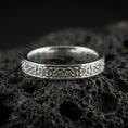 Load image into Gallery viewer, Polished silver Celtic knot band ring on volcanic stone, crisp macro shot emphasizing clean shine, smooth edges, and detailed knotwork.